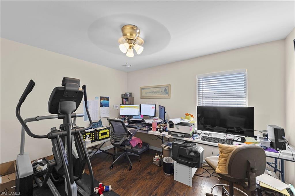 Home office with dark wood-style flooring and a ceiling fan
