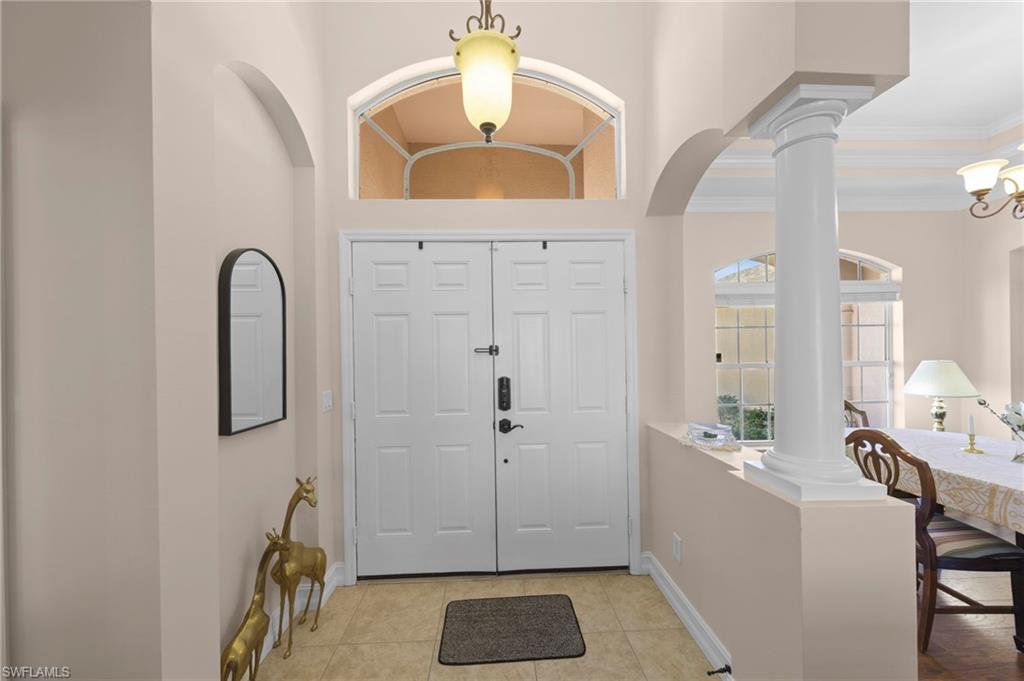 Foyer featuring decorative columns and light tile patterned floors