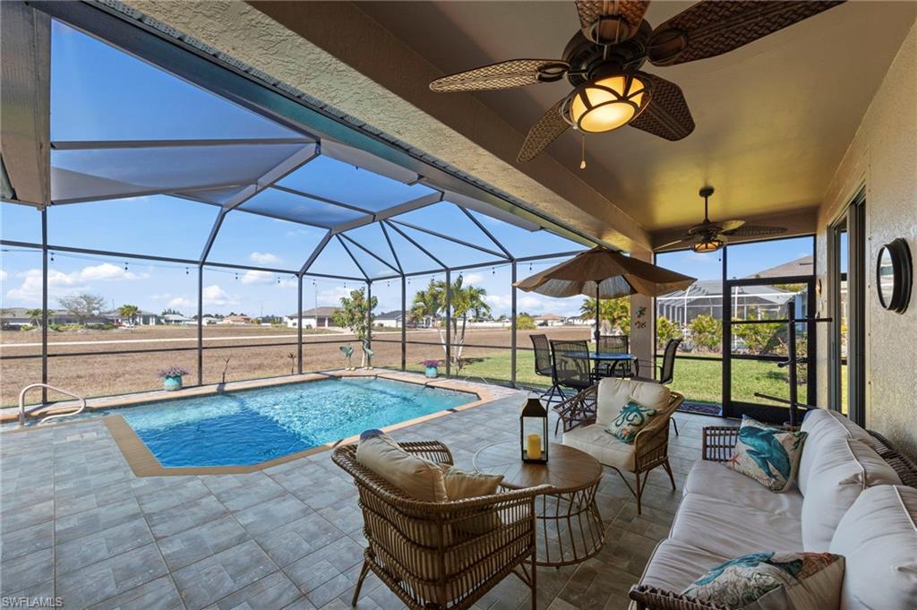 Outdoor pool featuring glass enclosure, a sunroom, a patio, outdoor lounge area, and a lawn