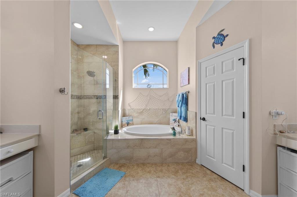 Bathroom with vanity, a shower stall, a garden tub, and light tile patterned flooring