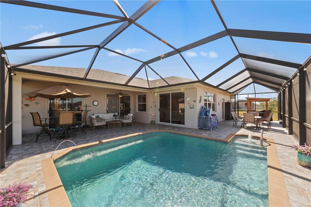 Swimming pool featuring an outdoor living / dining area, a sunroom, a patio, and glass enclosure