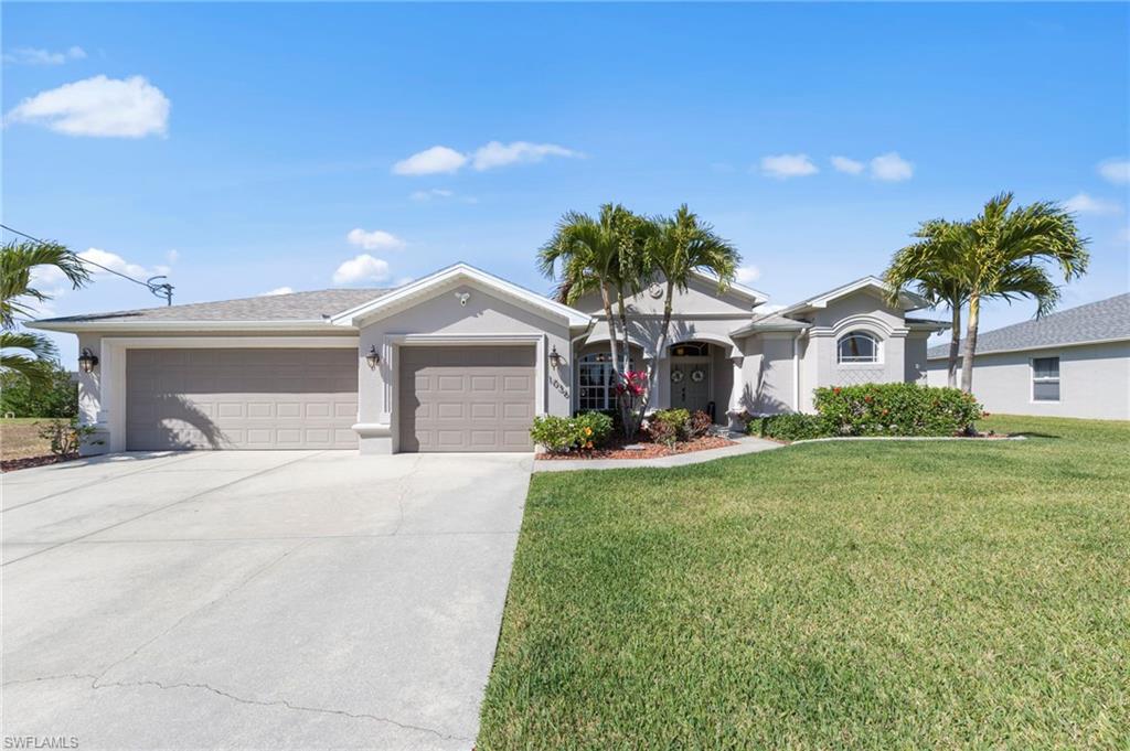 Single story home with a garage, driveway, stucco siding, and a front yard