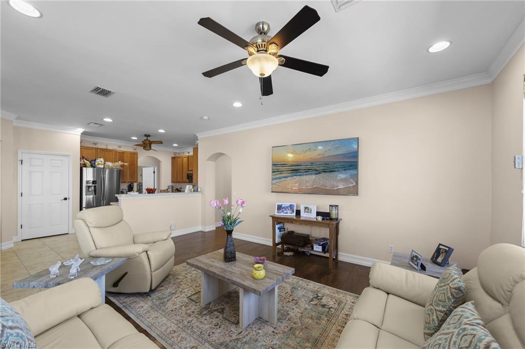 Living area with a ceiling fan, recessed lighting, ornamental molding, arched walkways, and wood finished floors