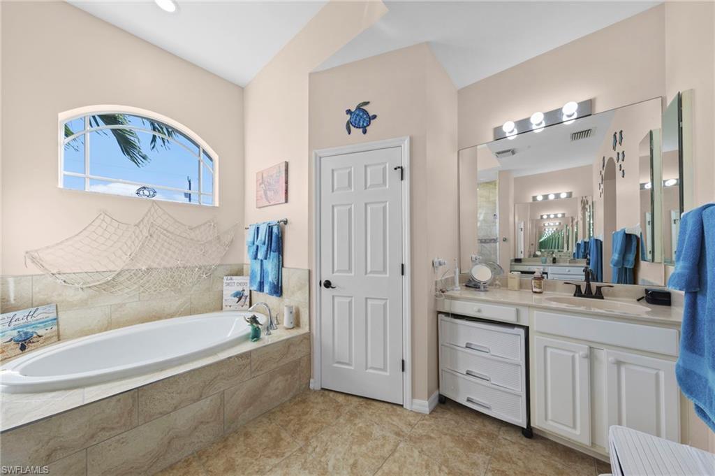 Bathroom with vanity, a garden tub, and light tile patterned floors
