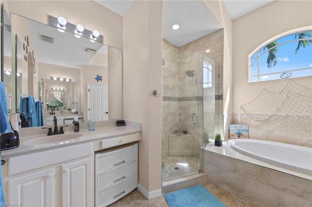 Bathroom with a stall shower, vanity, a bath, and light tile patterned flooring