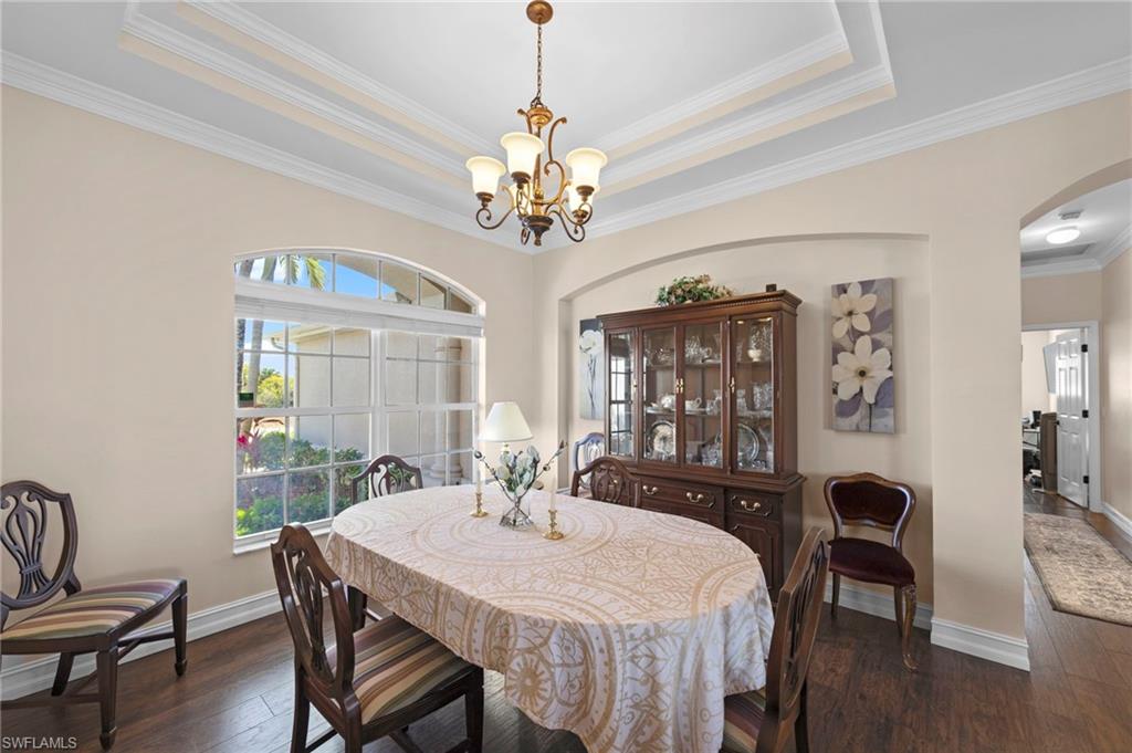 Dining room featuring dark wood-type flooring, arched walkways, ornamental molding, and hanging lights