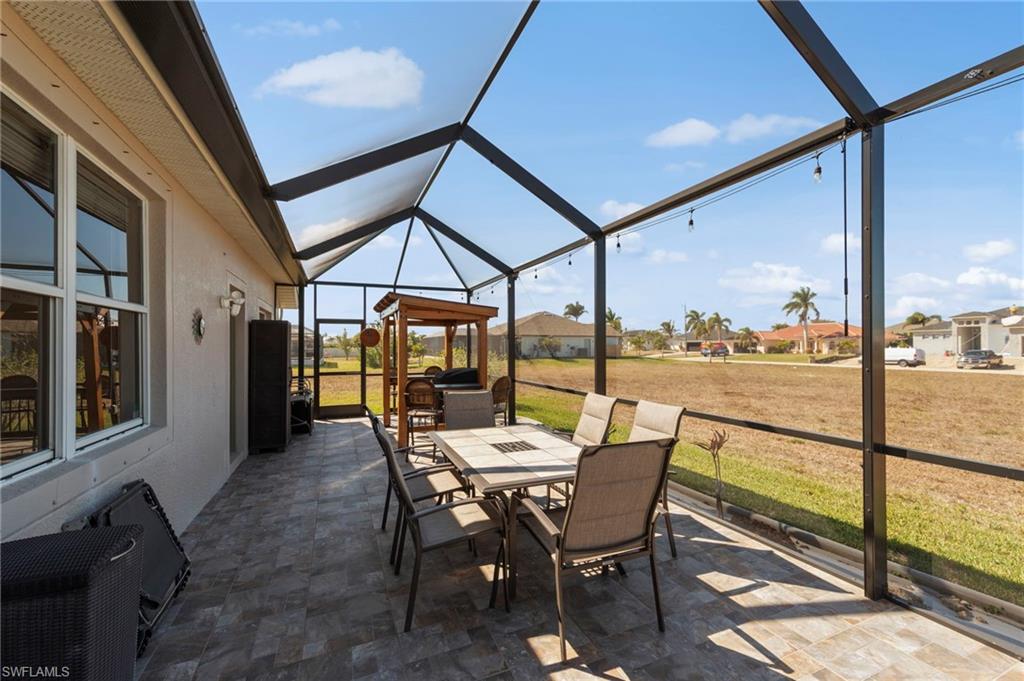 View of patio / terrace with a lanai, a sunroom, outdoor dining space, and a residential view