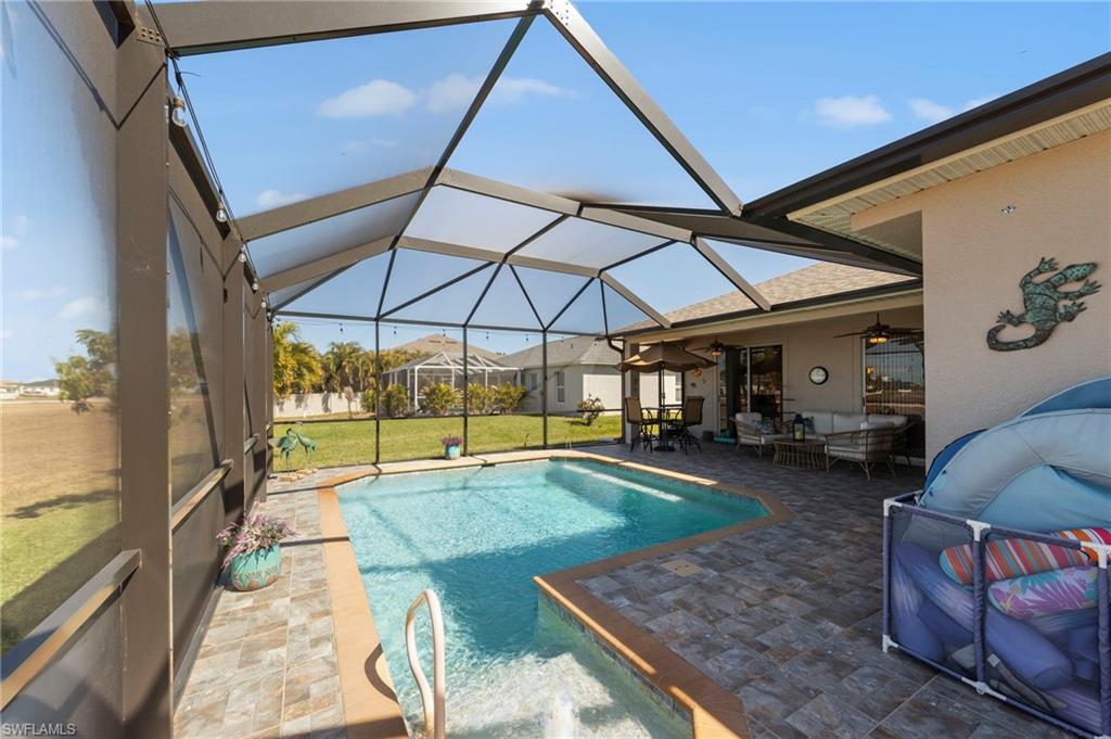 Swimming pool featuring a patio, outdoor lounge area, a sunroom, a lawn, and glass enclosure
