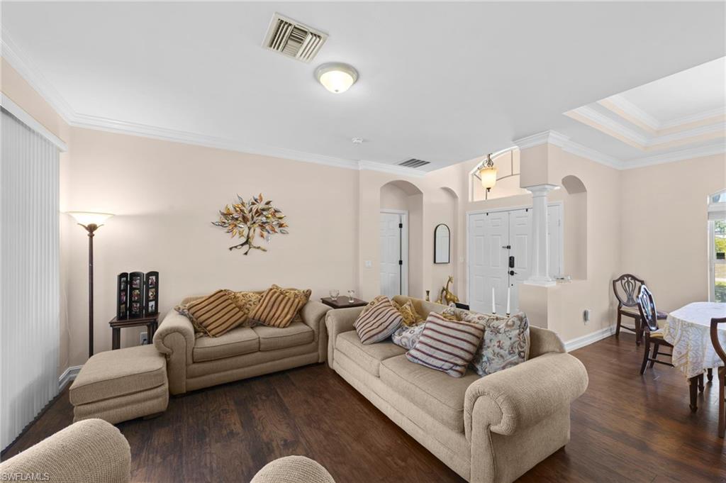 Living room featuring crown molding, arched walkways, and dark wood-type flooring
