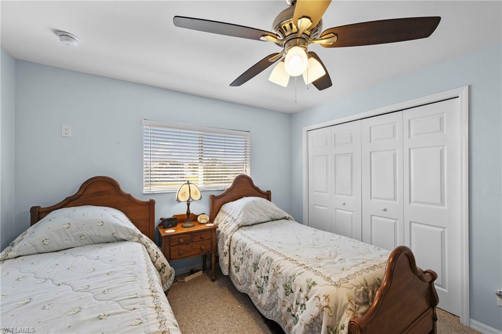 Carpeted bedroom with a closet and ceiling fan