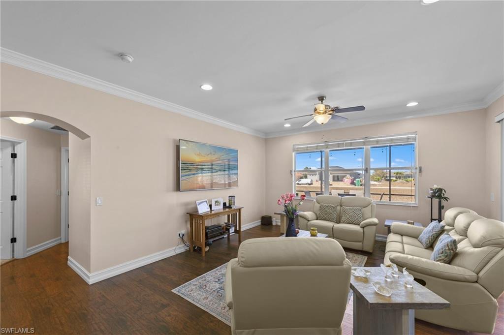 Living area featuring arched walkways, ornamental molding, wood finished floors, ceiling fan, and recessed lighting