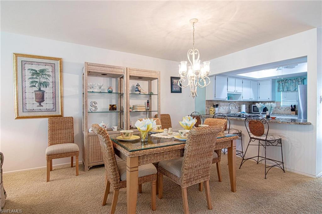 Dining space featuring light colored carpet and hanging lights
