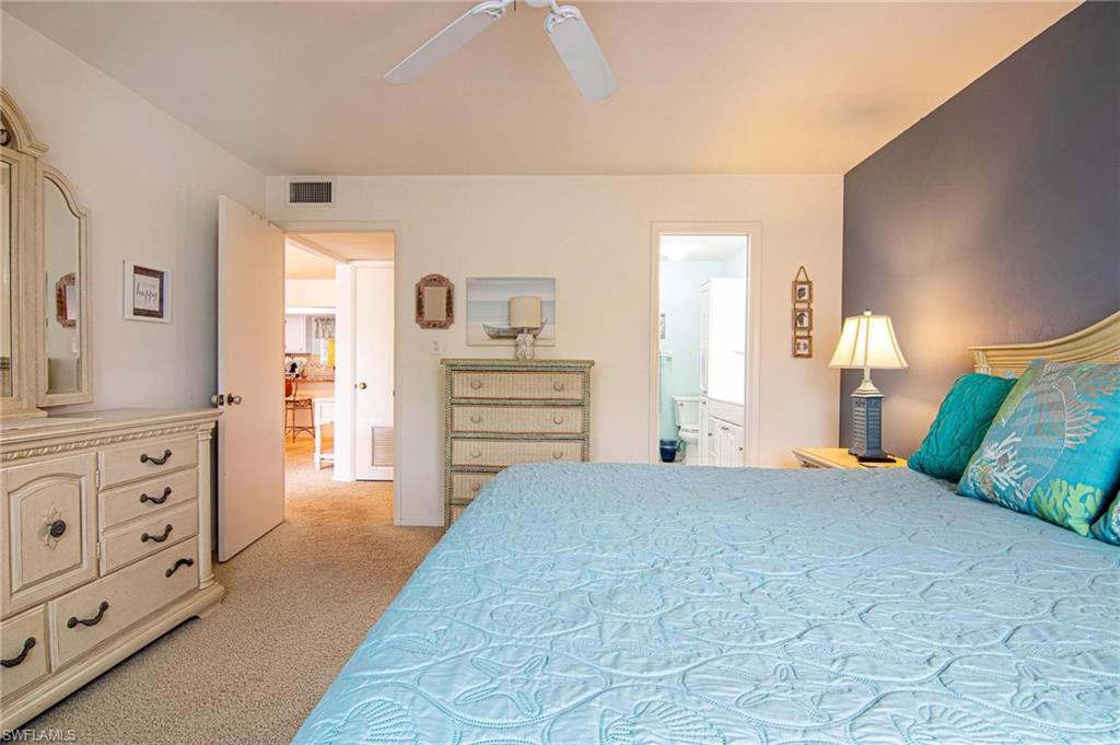 Bedroom featuring light carpet, ensuite bath, and a ceiling fan
