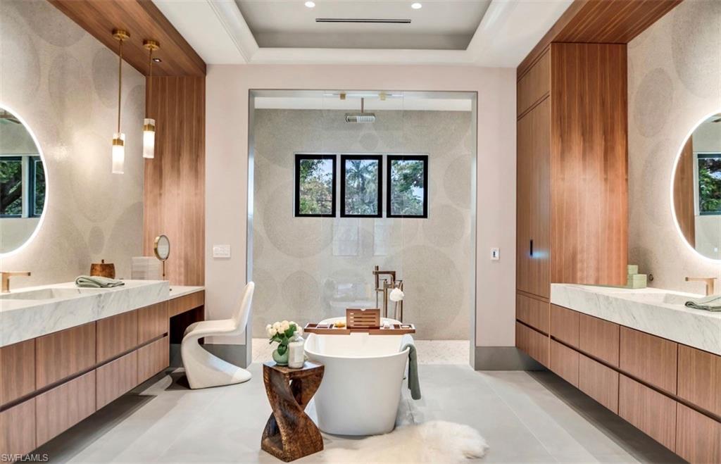 As stunning primary bath with dual floating vanities and integrated sinks, slipper tub, and custom walnut cabinetry. Oversized shower wrapped in porcelain and a waterjet marble floor, and two frosted glass water closets