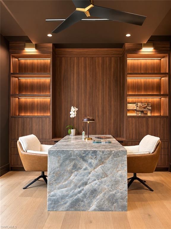 Home office with waterfall stone desk and built-in dual lit shelving
