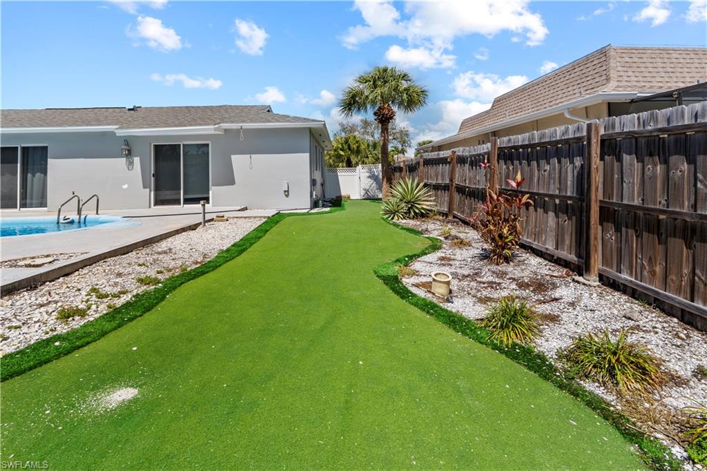 Rear view of house with a patio area, stucco siding, a fenced backyard, and an area to practice putting