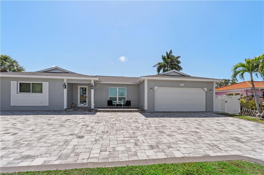 Ranch-style home featuring an attached garage, decorative driveway, stucco siding, and a gate
