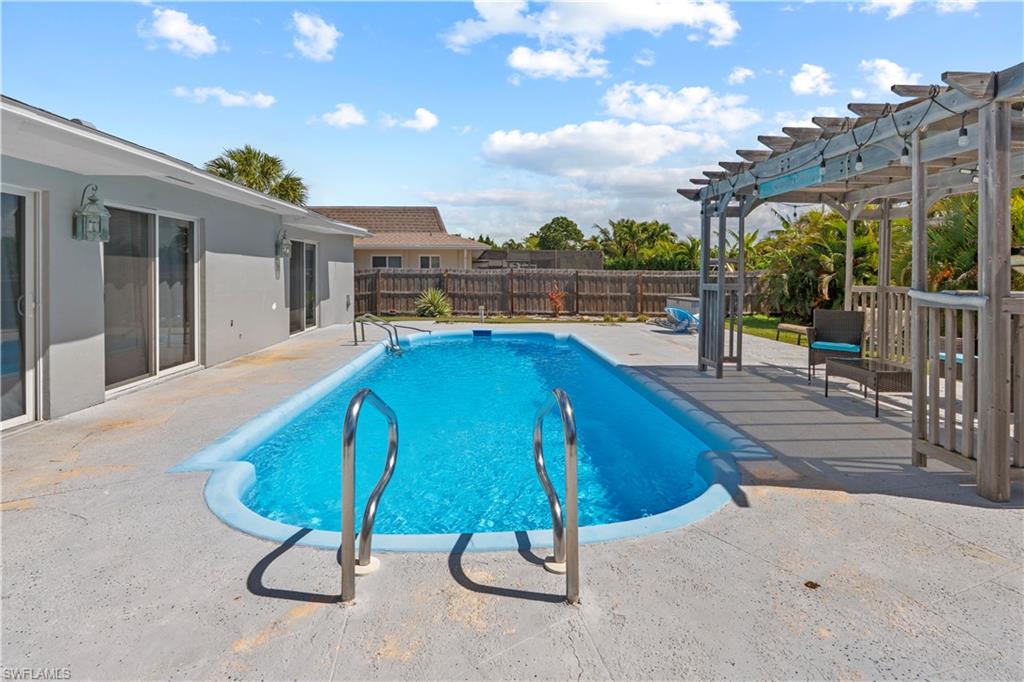 View of pool featuring patio surround, a pergola, and a fenced backyard