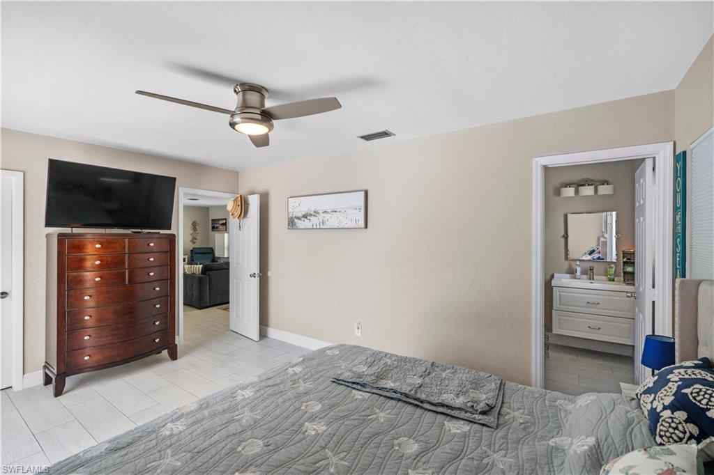 Bedroom featuring connected bathroom, a ceiling fan, and wood tiled floors