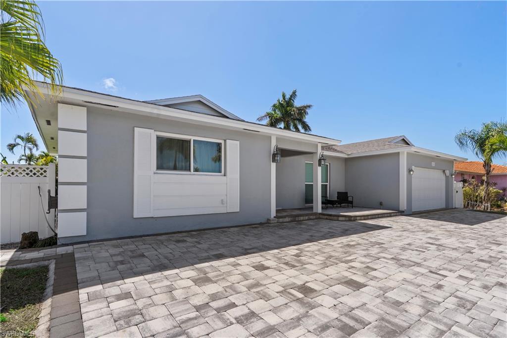 Ranch-style house with an attached garage, stucco siding, driveway, and a patio area