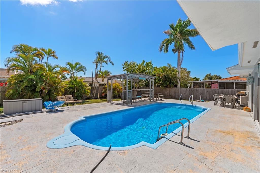 View of pool with patio surround, a fenced backyard, and a pergola