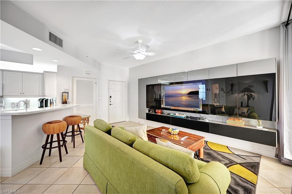 Living room with a ceiling fan and light tile patterned flooring
