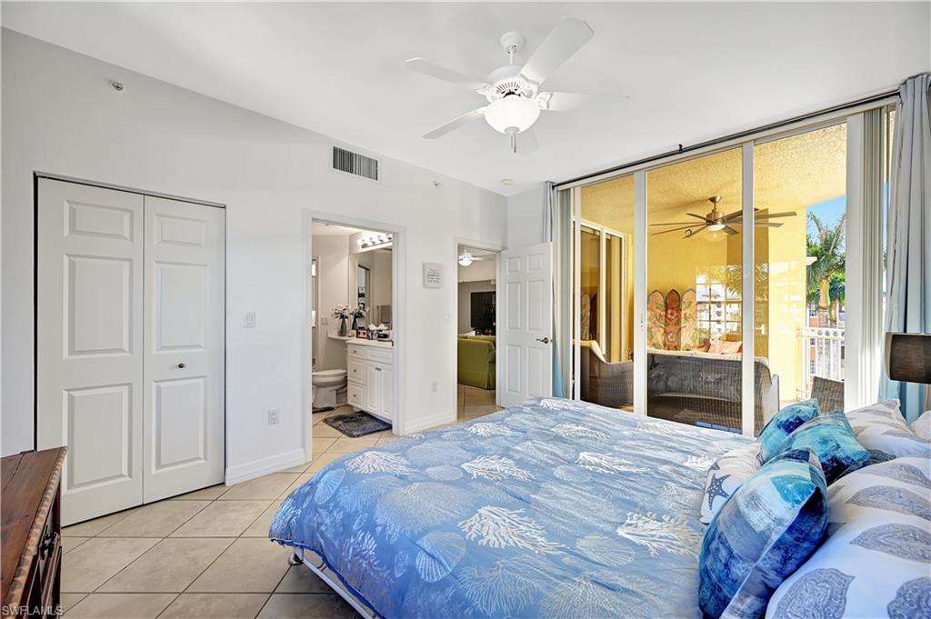 Bedroom featuring light tile patterned floors, ceiling fan, ensuite bathroom, and access to outside
