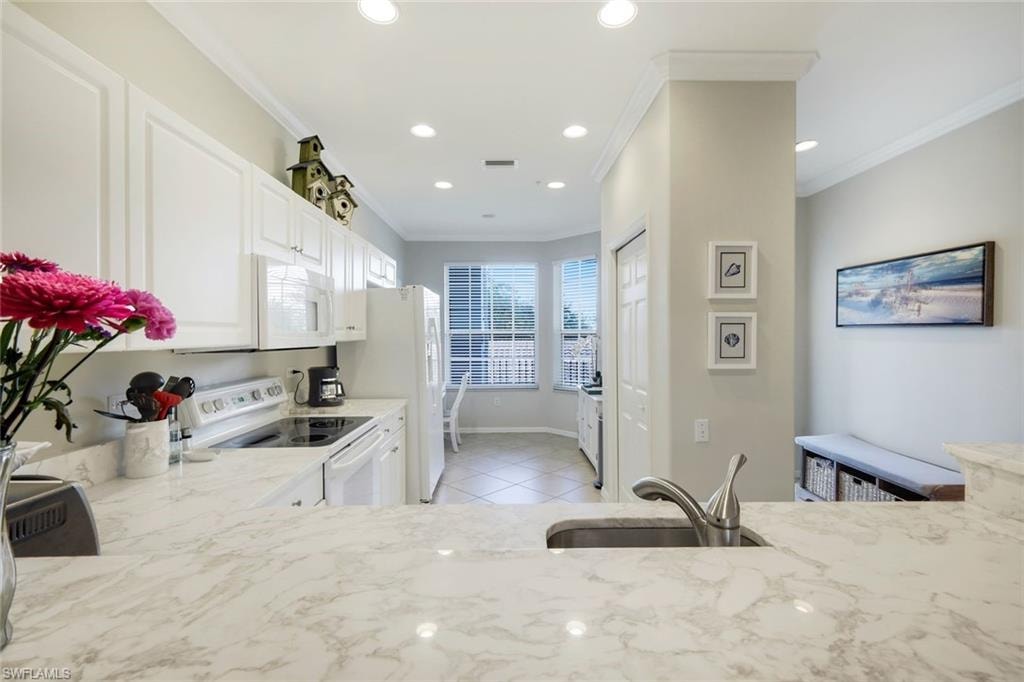 Kitchen featuring white appliances, white cabinets, crown molding, recessed lighting, and light tile patterned flooring