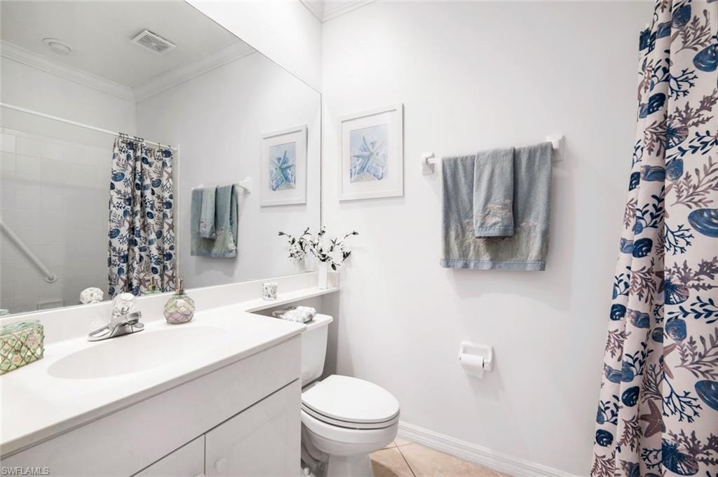 Bathroom featuring vanity, curtained shower, ornamental molding, and light tile patterned flooring