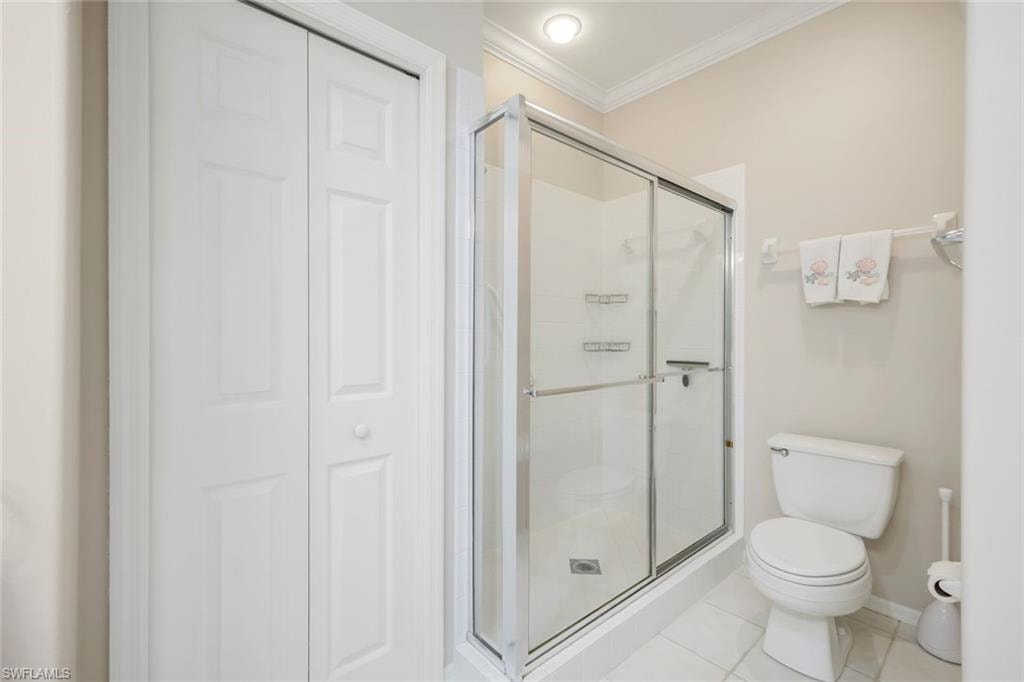 Full bath with a closet, ornamental molding, a shower stall, and light tile patterned floors