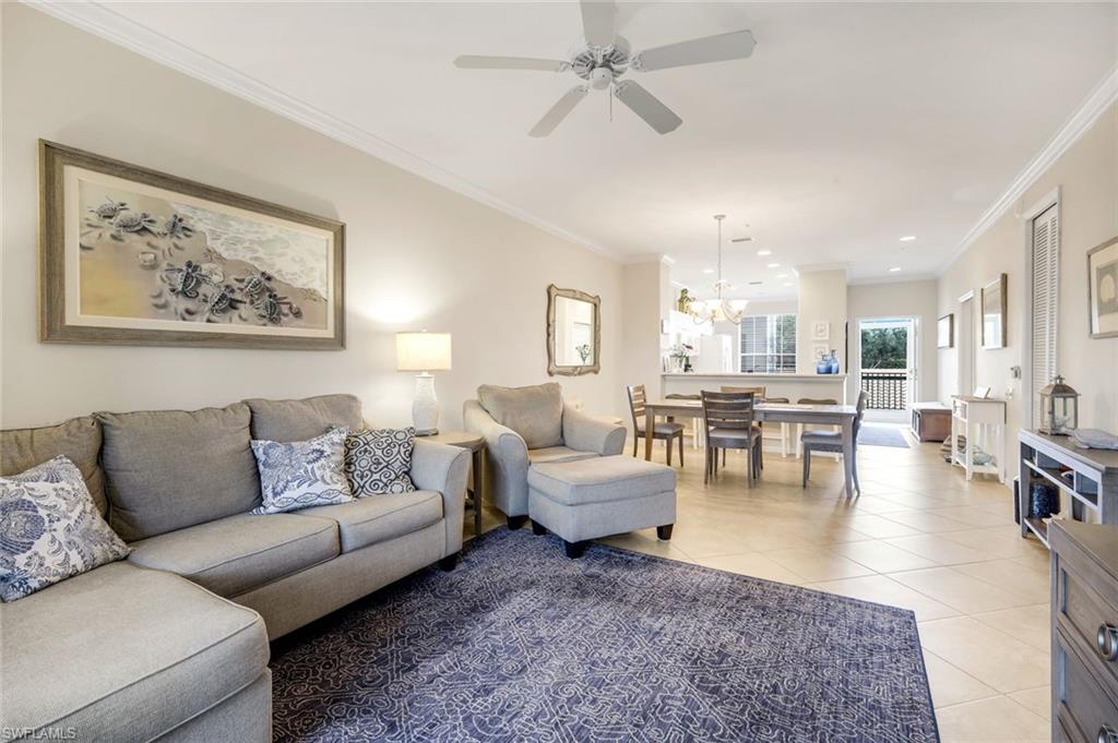 Living room featuring ornamental molding, ceiling fan, light tile patterned floors, and a chandelier