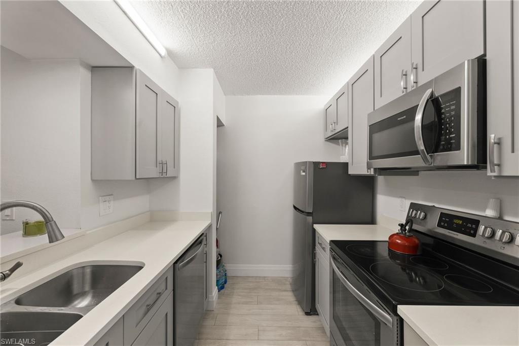 Kitchen featuring stainless steel appliances, gray cabinets, and a textured ceiling