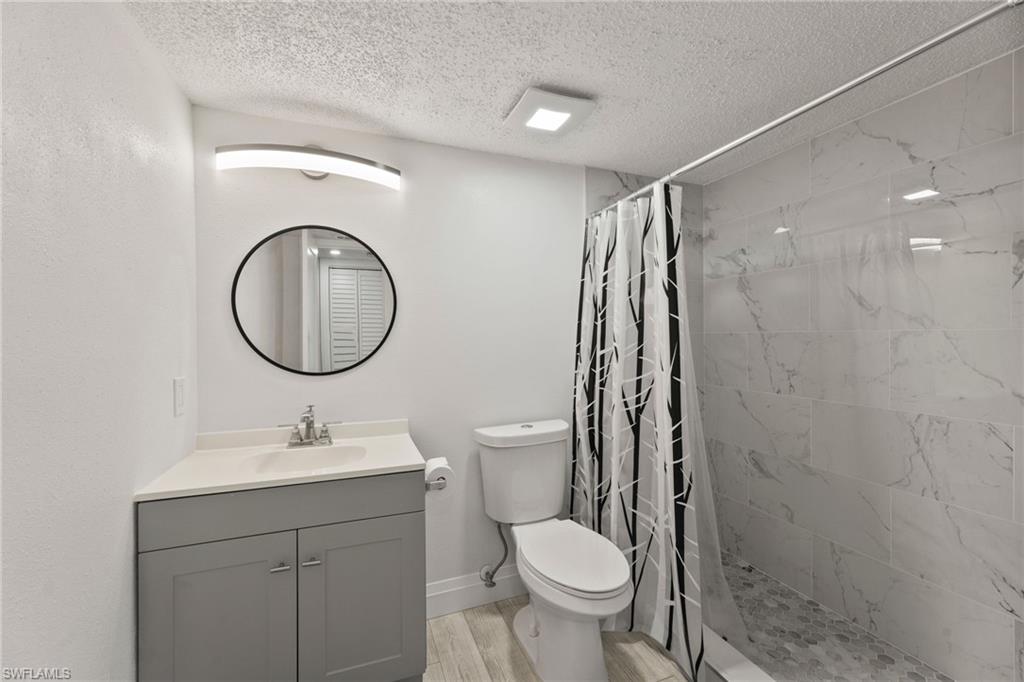 Bathroom featuring vanity, a stall shower, a textured ceiling, and light wood-style floors