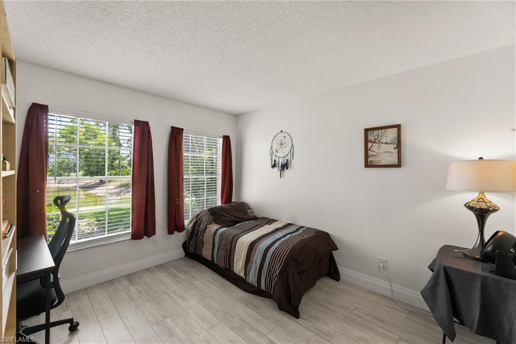 Bedroom featuring light wood-type flooring, an office area, and a textured ceiling