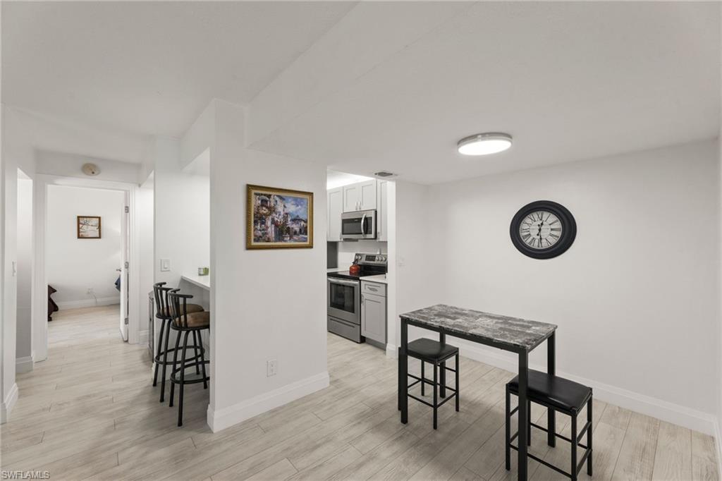 Kitchen featuring stainless steel appliances, a kitchen breakfast bar, light countertops, light wood-style floors, and a peninsula