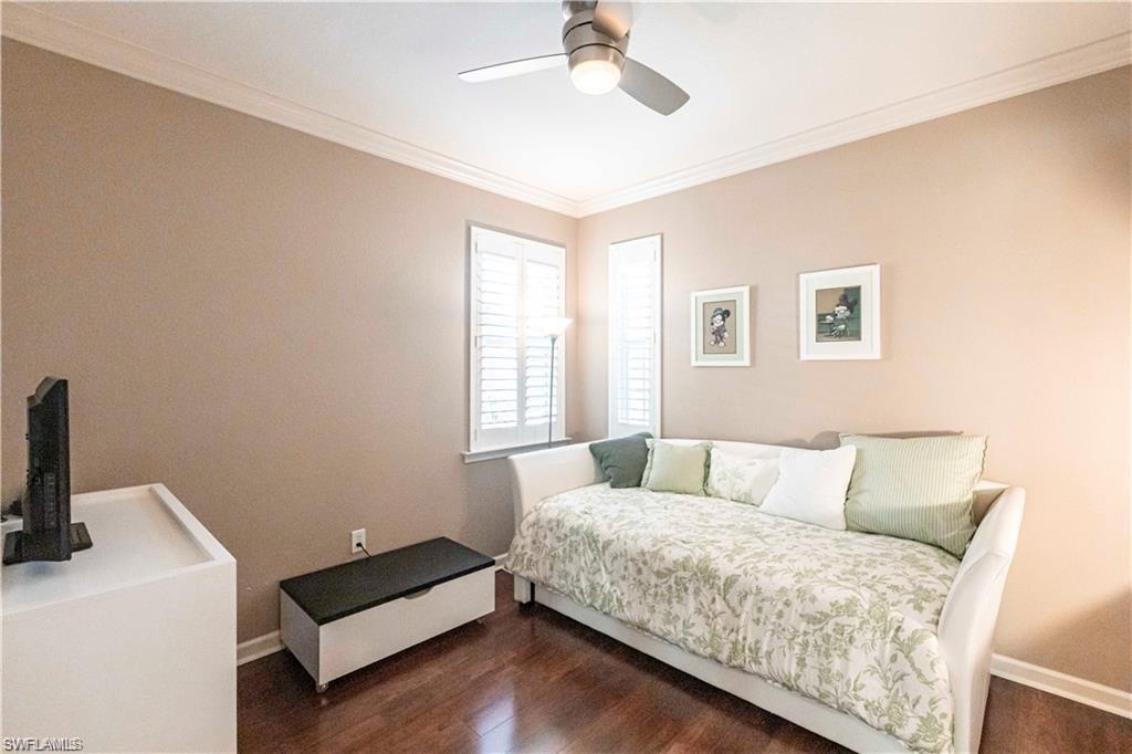 Bedroom featuring ornamental molding, dark wood-style flooring, and ceiling fan