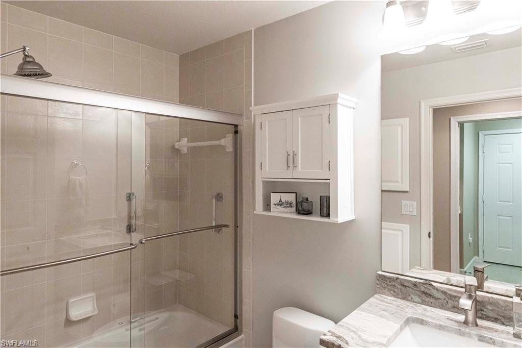 Bathroom featuring combined bath / shower with glass door and vanity