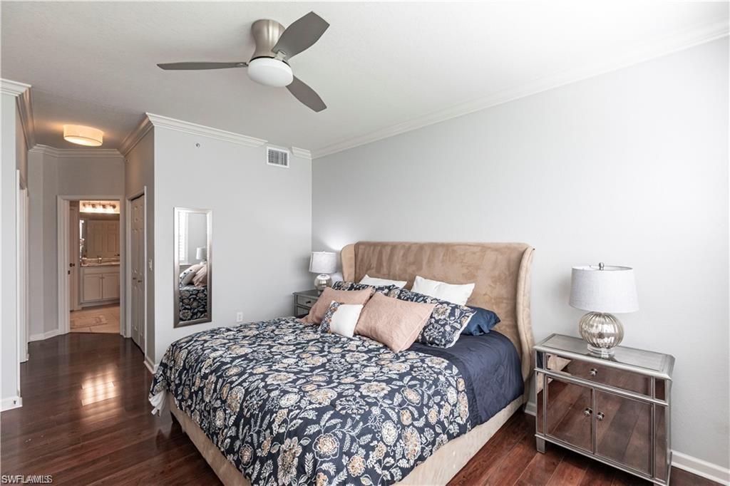 Bedroom featuring crown molding, a closet, ensuite bath, dark wood-type flooring, and ceiling fan