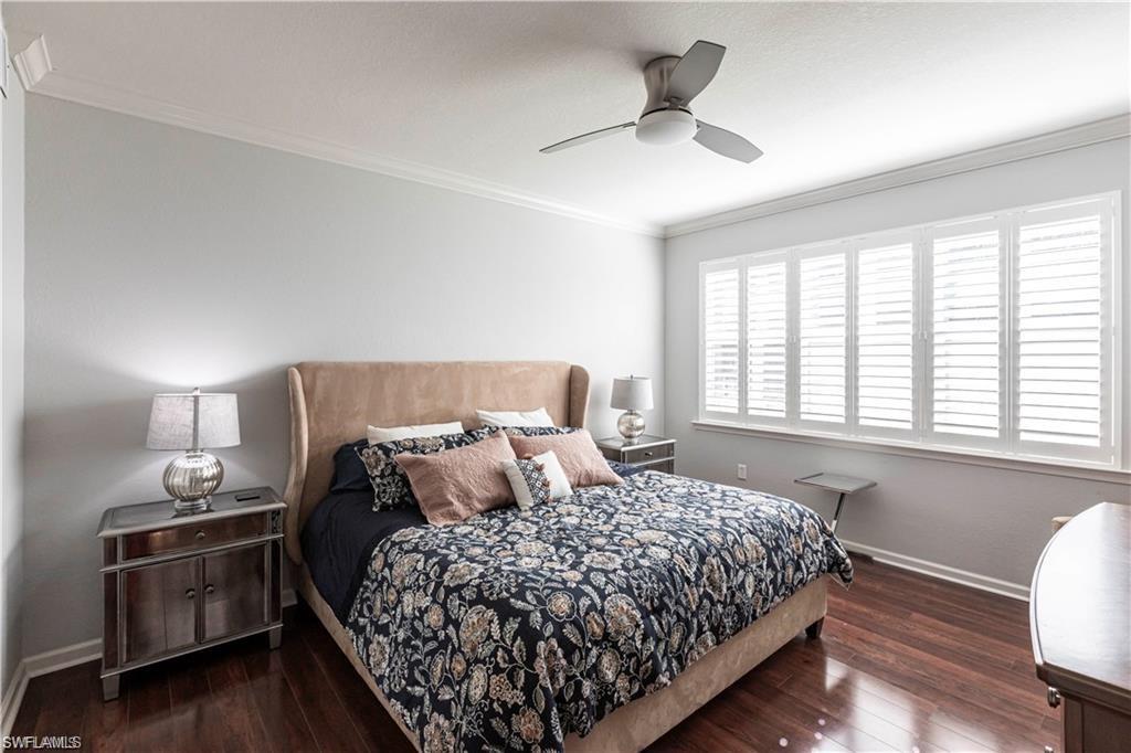 Bedroom with ornamental molding, dark wood-style flooring, and a ceiling fan