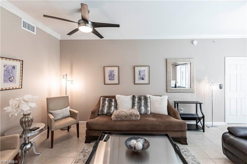 Living area featuring light tile patterned flooring, ornamental molding, and a ceiling fan