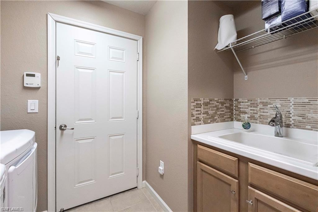 Laundry area featuring a sink and light tile patterned flooring