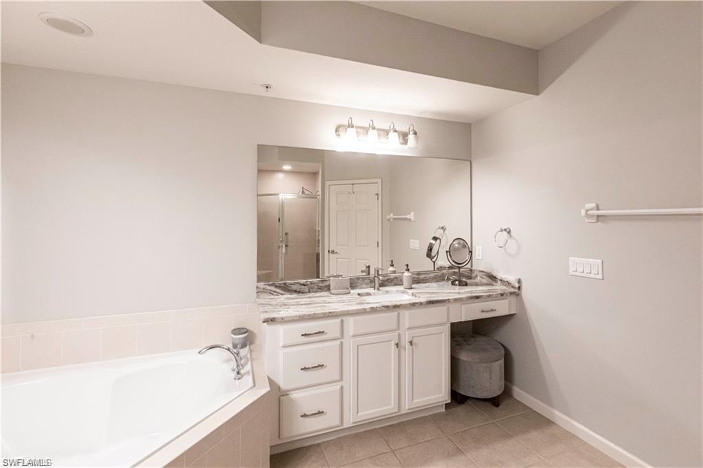 Full bath with vanity, a garden tub, light tile patterned flooring, and a shower stall