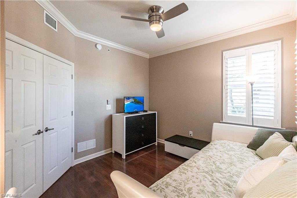 Bedroom with dark wood-style floors, crown molding, and a ceiling fan