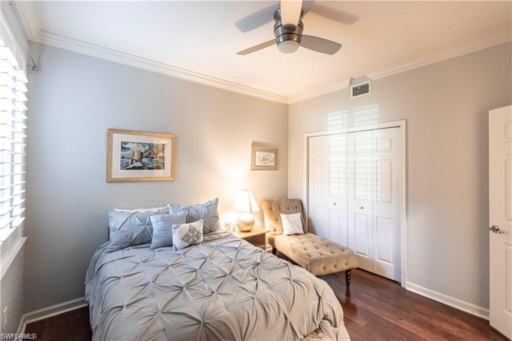 Bedroom featuring crown molding, a closet, dark wood finished floors, and ceiling fan