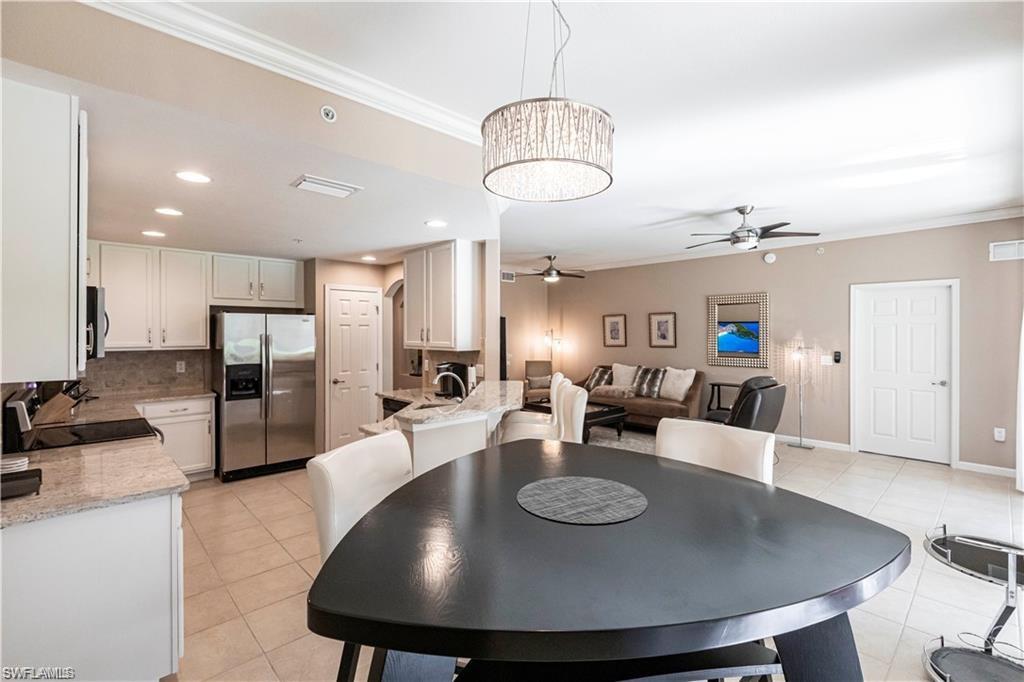 Dining room with crown molding, light tile patterned flooring, a ceiling fan, and suspended lighting