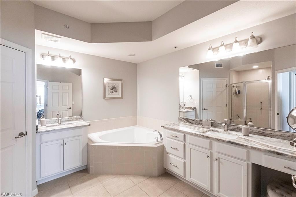 Bathroom with two vanities, a shower stall, a bath, and light tile patterned flooring