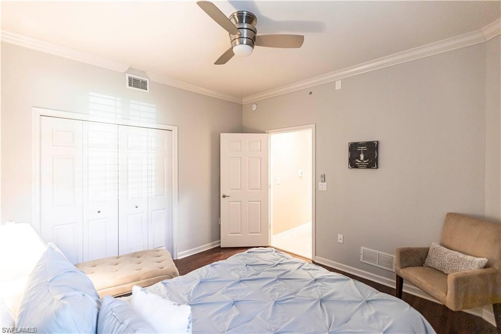Bedroom with ornamental molding, a closet, a ceiling fan, and dark wood finished floors