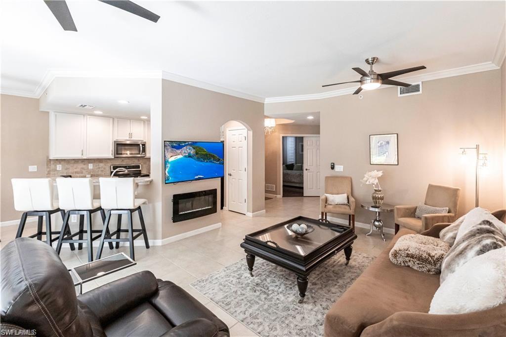 Living area featuring a ceiling fan, crown molding, light tile patterned floors, recessed lighting, and arched walkways