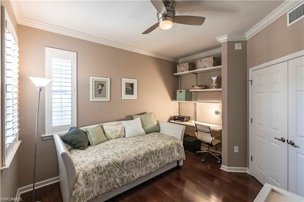 Bedroom with crown molding, dark wood finished floors, a ceiling fan, a closet, and built in study area