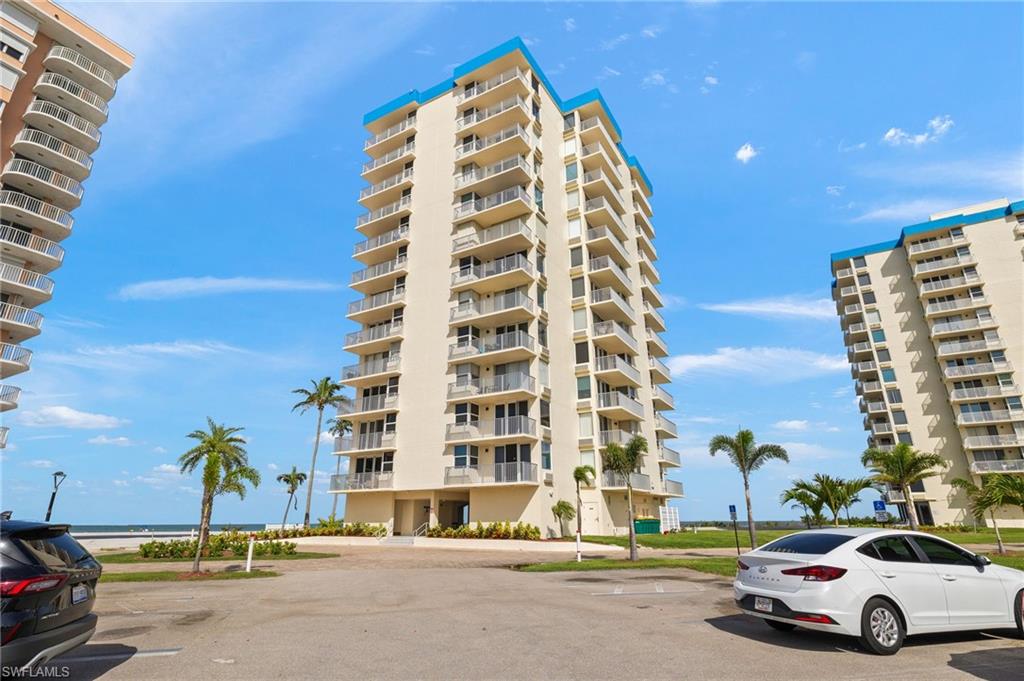 View of apartment building / complex featuring uncovered parking